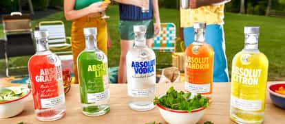 Five different Absolut Vodka bottles with different flavors with people in the background