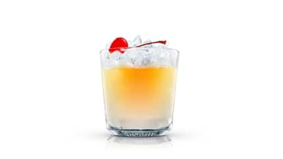 Absolut Peach Surrender in a textured rocks glass with ice and a cherry garnish on a wooden table