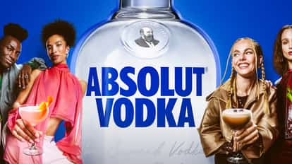 Absolut Vodka bottle in the center against a blue background. To the right, one woman holds an Absolut Cosmo and another woman holds an Espresso Martini. To the left, a woman holds a Bloody Mary and a man holds an Absolut Mule.