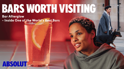 Promotional banner for “Bars Worth Visiting – Bar Afterglow” showing a sparkling citrus cocktail in a tall glass, a close-up of a smiling bartender in soft red lighting and a city street scene in the background.
