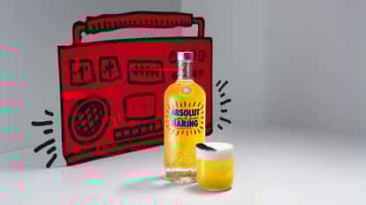 A bottle of Absolut Haring stands on a table next to a Haring Fizz. In the background, there is a vintage red boombox.