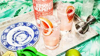 Two Paloma cocktails on a tray and a bottle of Absolut Grapefruit next to them