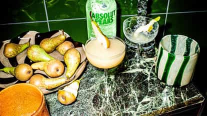 Absolut Pears Martini in a coupe glass garnished with a pear slice on a marble countertop