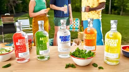 Five different Absolut Vodka bottles with different flavors with people in the background