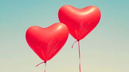 Banner for Valentine's Day cocktails featuring two red heart-shaped balloons floating in the sky.