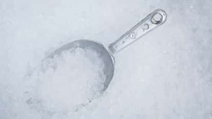 Metal scoop filled with crushed ice on a bed of ice.