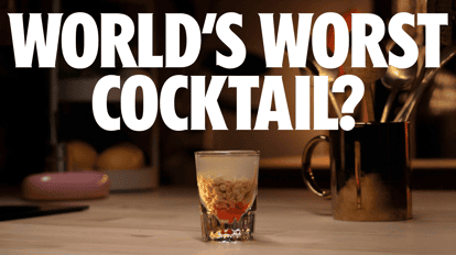 A shot glass with a layered cocktail resembling a ‘brain hemorrhage’ drink on a wooden bar counter, with large bold text reading ‘WORLD’S WORST COCKTAIL?’ in the background.