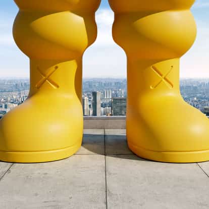 KAWS' Chum stands atop a building overlooking a city, with ABSOLUT XX letters inset below.