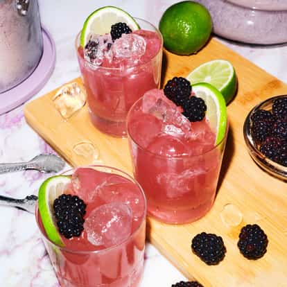 Three Absolut Wild Berri Vodkarita cocktails surrounded by fresh blackberries