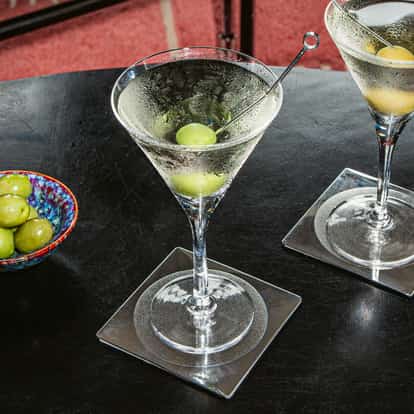 Absolut Martini served in two chilled martini glasses garnished with olives and a vodka bottle on a couch
