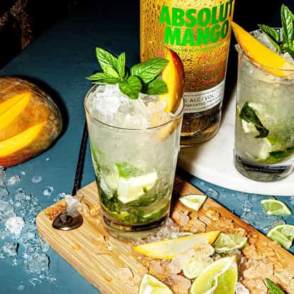 Absolut Mango Mojito served in a highball glass with crushed ice mint sprig mango wedge and lime pieces