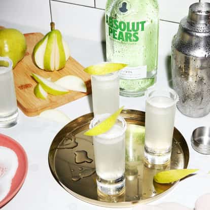 Absolut Pear Drop in sugar-rimmed shot glasses on a brass tray with pear slices and a bottle