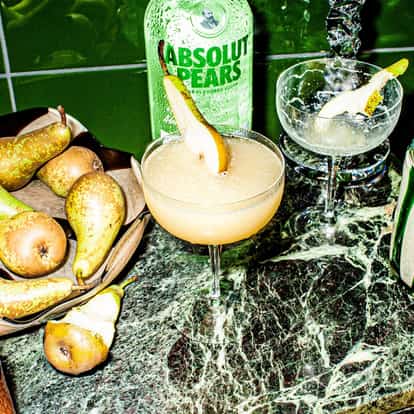 Absolut Pears Martini in a coupe glass garnished with a pear slice on a marble countertop