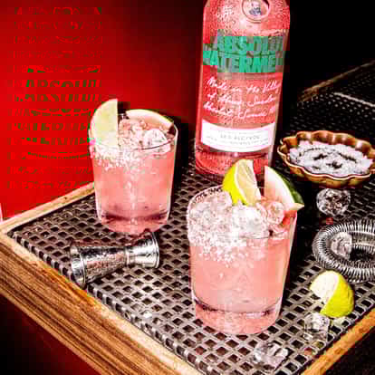 Watermelon Vodkarita in a rocks glass next to a bottle of Absolut Watermelon.
