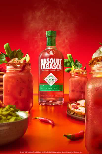 ABSOLUT® TABASCO™ bottle surrounded by Bloody Mary cocktails in jam jars with garnishes, brunch foods, and a vibrant red background