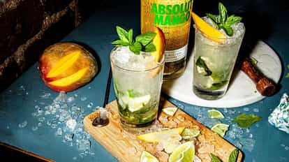 Absolut Mango Mojito served in a highball glass with crushed ice mint sprig mango wedge and lime pieces