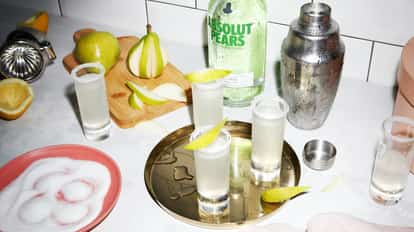 Absolut Pear Drop in sugar-rimmed shot glasses on a brass tray with pear slices and a bottle