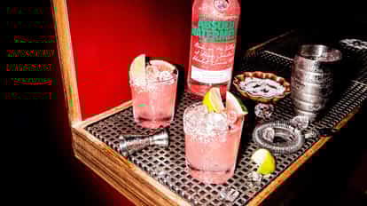 Watermelon Vodkarita in a rocks glass next to a bottle of Absolut Watermelon.